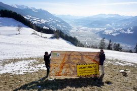 Zwei Aktivist:innen halten ein Banner vor einer weiten Winterlandschaft.