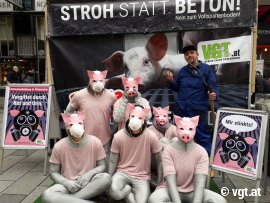 Aktivist_innen posieren als Schweinegruppe mit Bauer