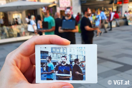 Ein Polaroidfoto einer Demo ist so fotografiert, dass man die Demo im Hintergrund verschwommen sehen kann.