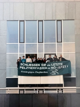Fassade eines Bürogebäudes, von dem Aktivist:inenn ein Banner halten