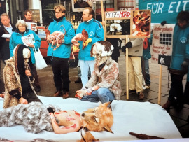 Eine halbnackte mit Blut verschmierte Aktivistin liegt am Boden während andere tote Pelztiere präsentieren